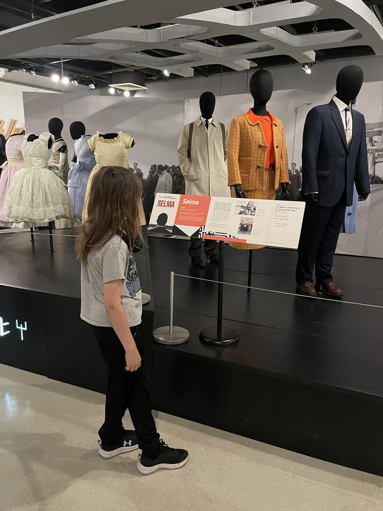 Student reads exhibit information beside costumes worn by historical figures and portrayed in films about the Civil Rights Movement.