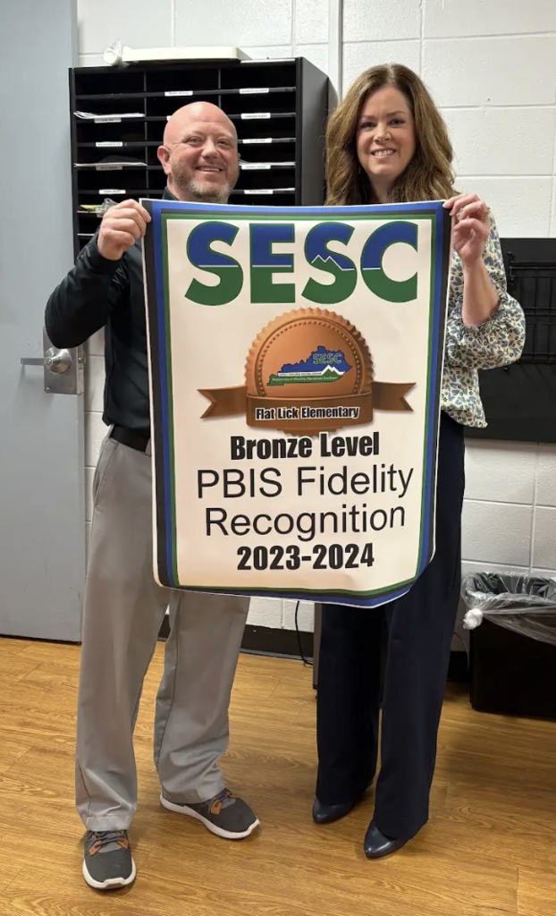 SESC Staff presenting a PBIS Fidelity Banner to Flat Lick Elementary Principal Jason Cornett