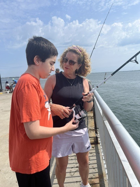 Teacher helping student with fishing pole