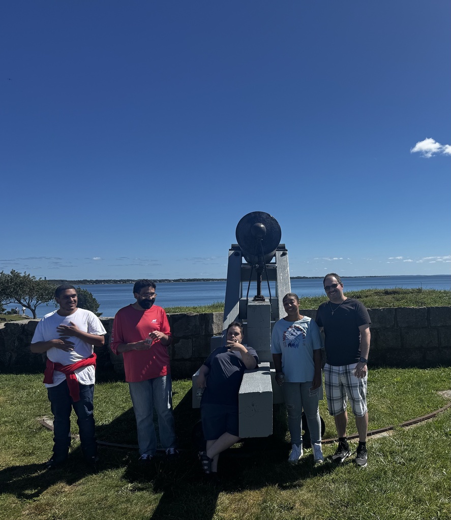 Men and women outdoors standing in front of a historic cannon