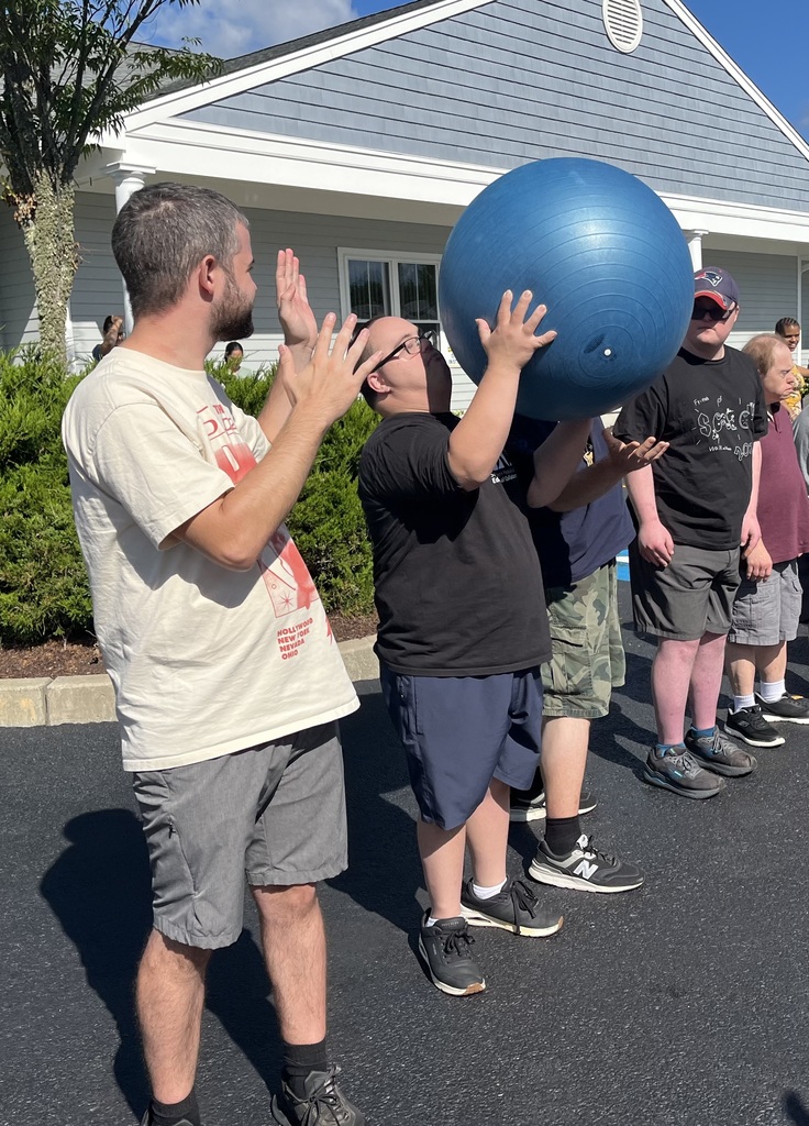 Group of men and women passing a ball over their heads 