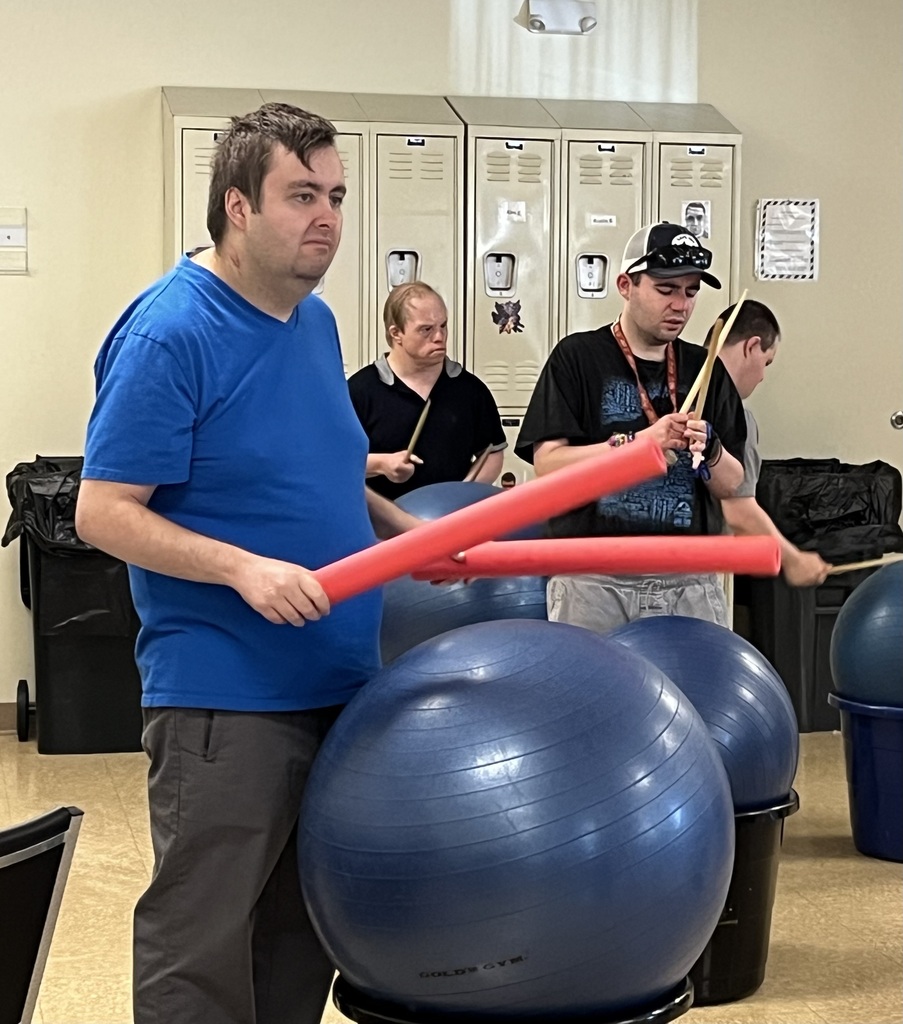 Group of men playing drums using a large plastic container and an exercise ball