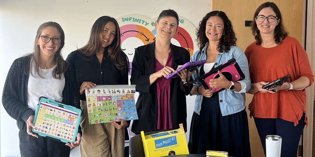 Five women hold communication tools while smiling