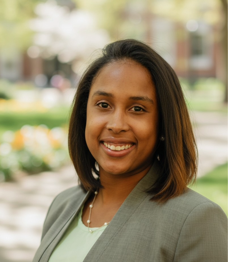 Executive Director of Talent & Community Affairs Carrols Perez is appearing in a blurred background photo wearing a suit jacket.