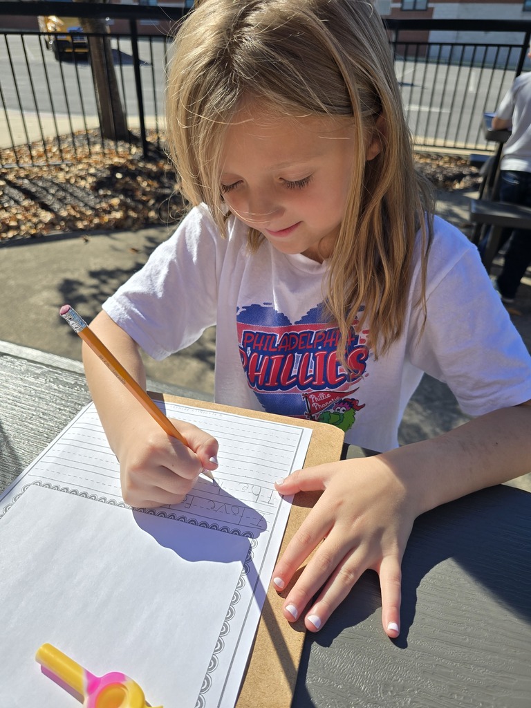 photo of students practicing their writing outdoors