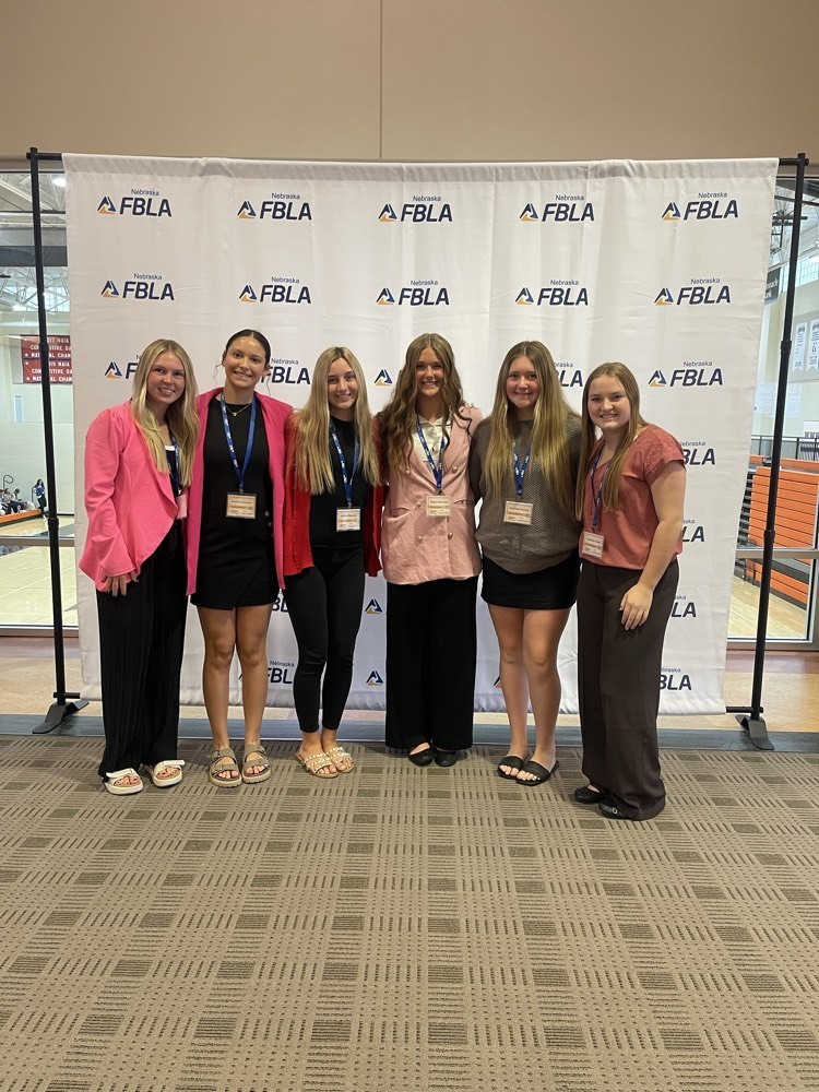 Six female high school students dressed professionally standing in front of FBLA backdrop.