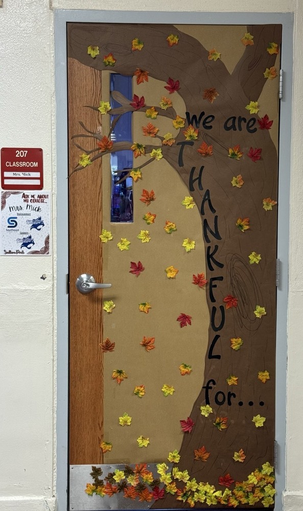 Classroom door with a tree and falling fall colored leaves on it.