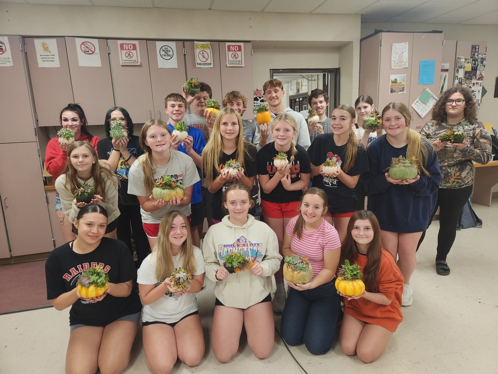 Student group photo holding their succulent decorated pumpkins.