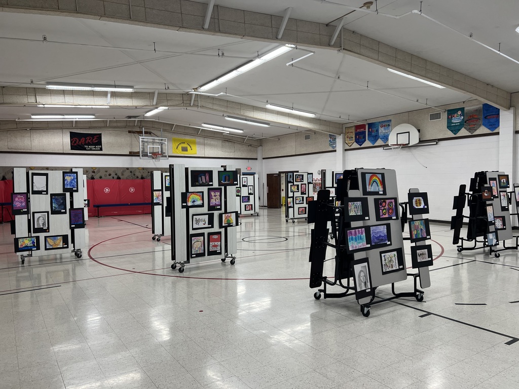 Art on display on lunch tables in a school gym