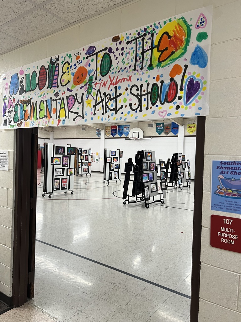 Art on display on lunch tables in a school gym
