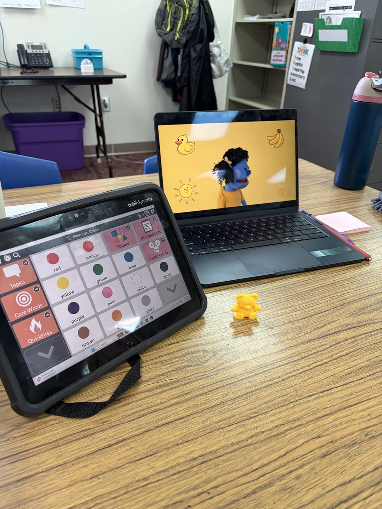 A communication device is set to color page, computer is showing a colors video, and a yellow bear is showing which color the video is showing