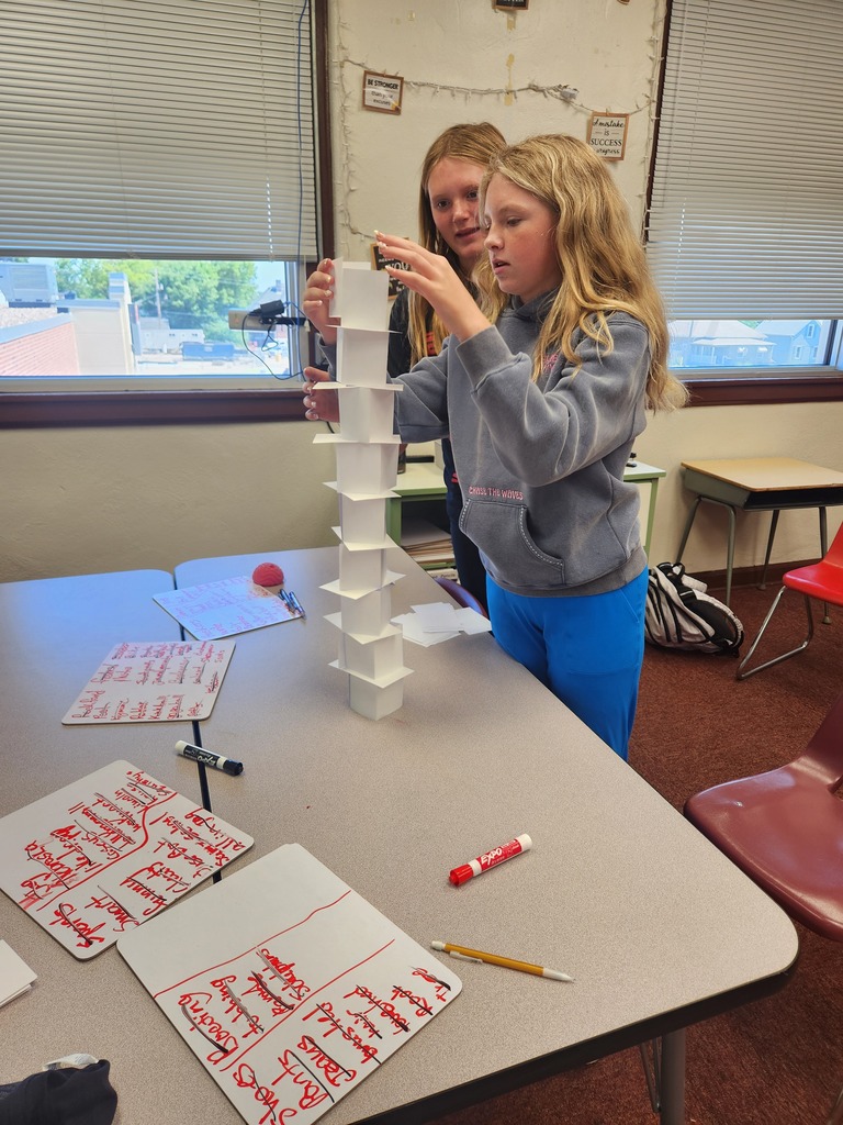 2 students standing creating their commonality tower out of index cards in a classroom setting