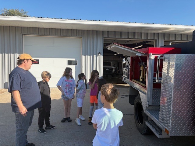 fire fighter showing students the truck and equipment