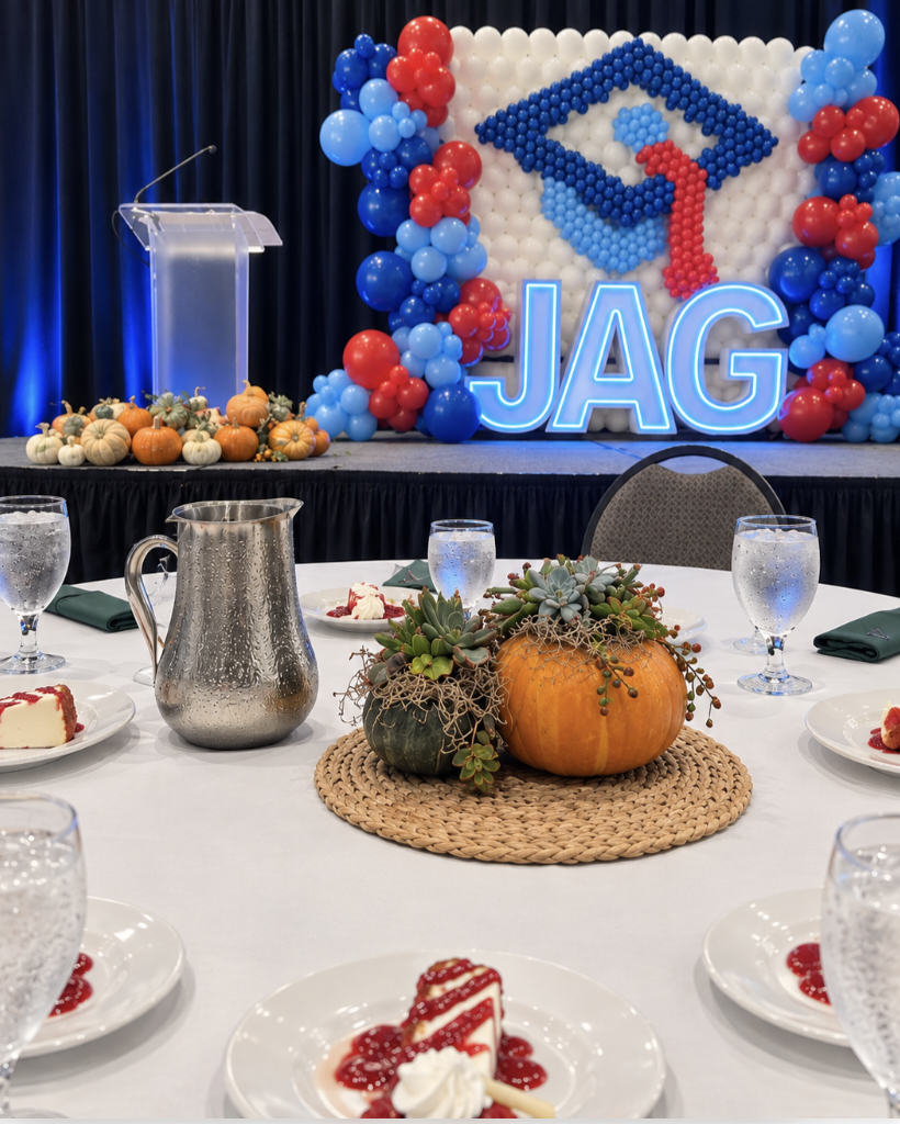 A picture highlighting the pumpkin centerpieces that were created with the stage and pumpkins on the stage in the background.