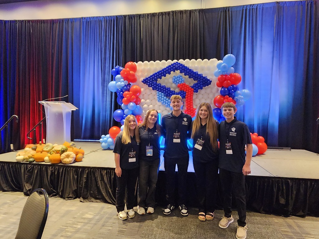5 JAG students standing in front of the front stage for a group photo before the leadership conference started.