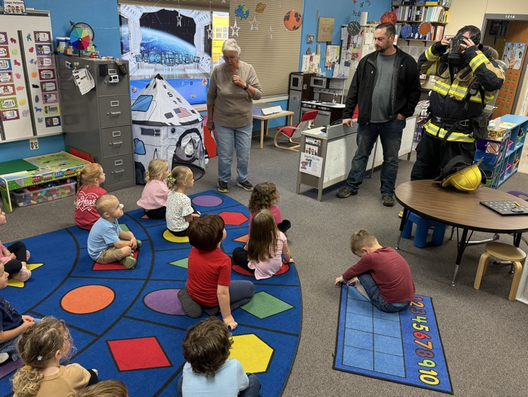 students in their classroom listening to the fire fighters