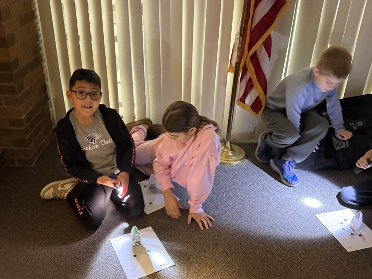First graders using flashlights to learn about shadows. 