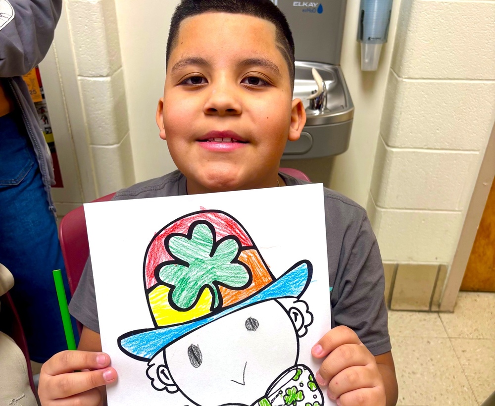 boy holds up leprechaun drawing