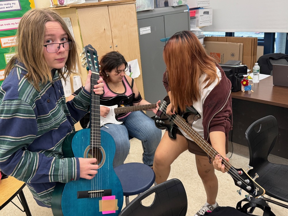 students play guitars, bass in classroom