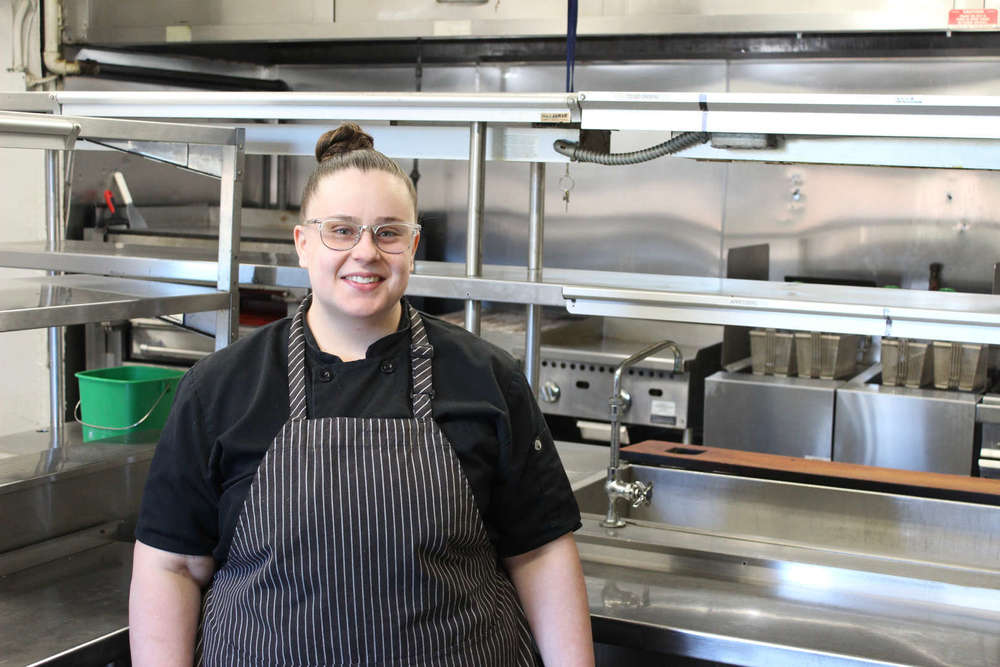 Catherine DiQuinzio posing in front of the kitchen she works in. 
