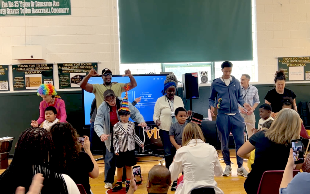 students perform for parents while teachers assist
