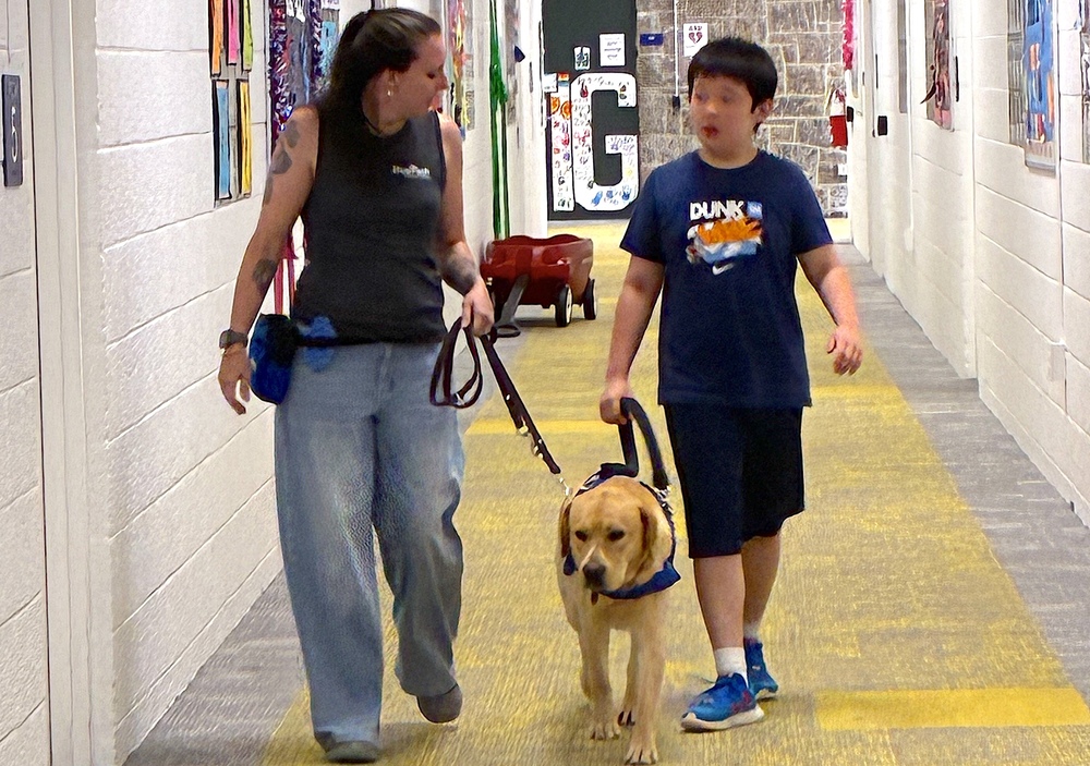 therapist and student walk school hallway with service dog