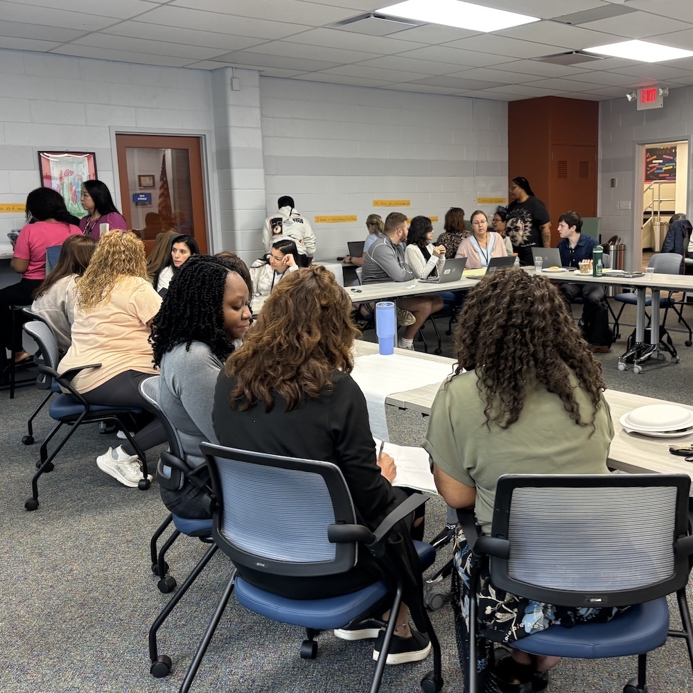Teachers work around a large table in a conference room