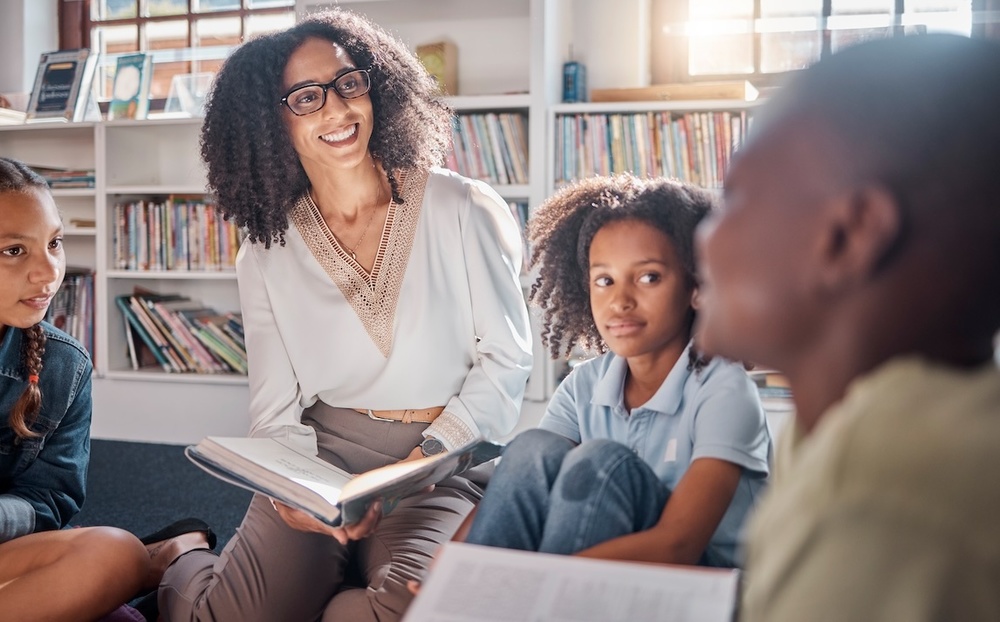 school librarian seated on floor with kids
