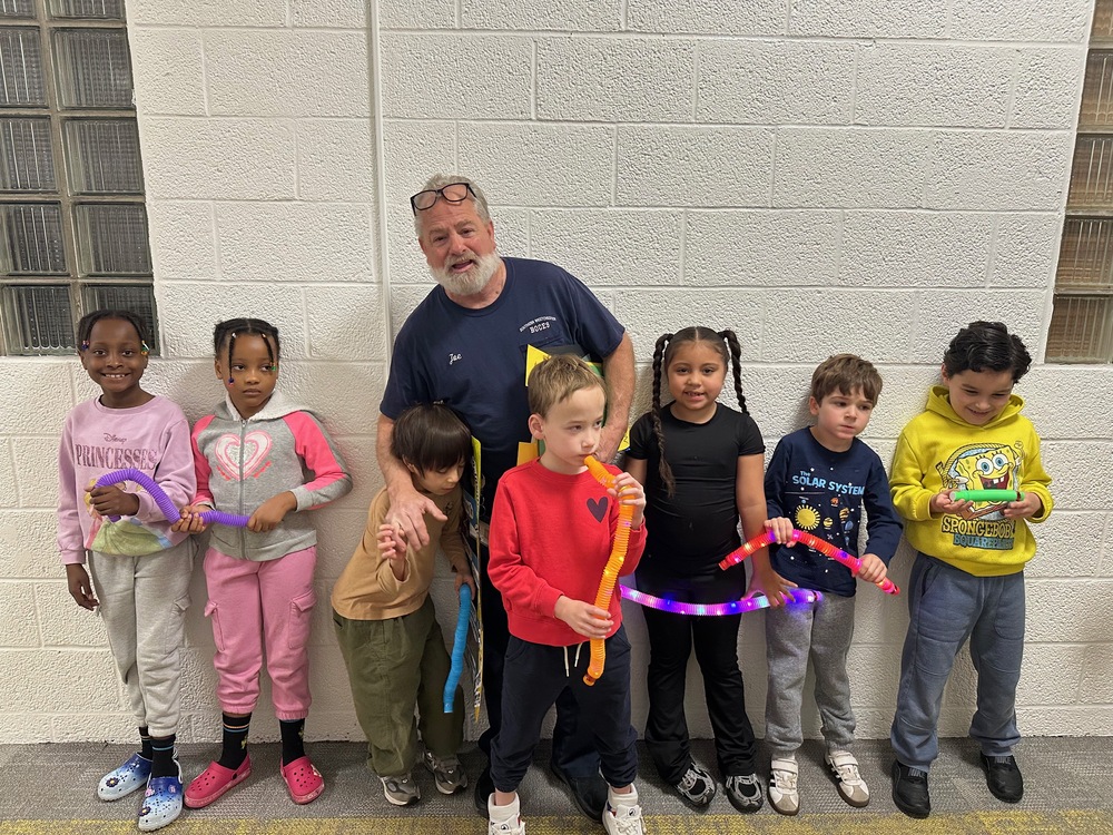custodian and students pose against wall