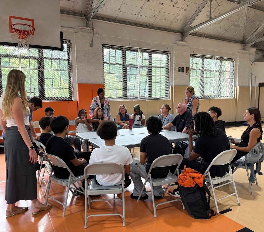teachers and students in a gym sitting around a table
