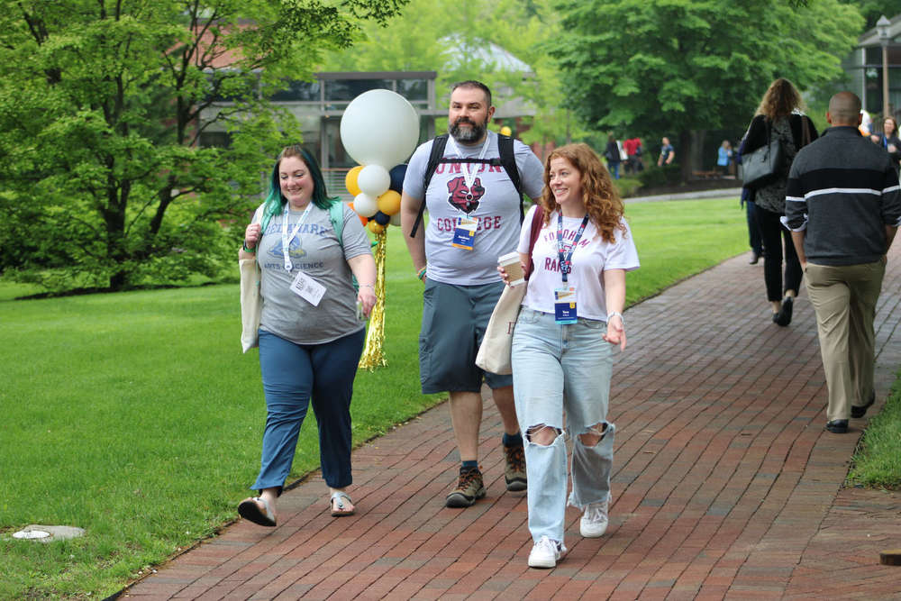 two women and one man walking on a path outside