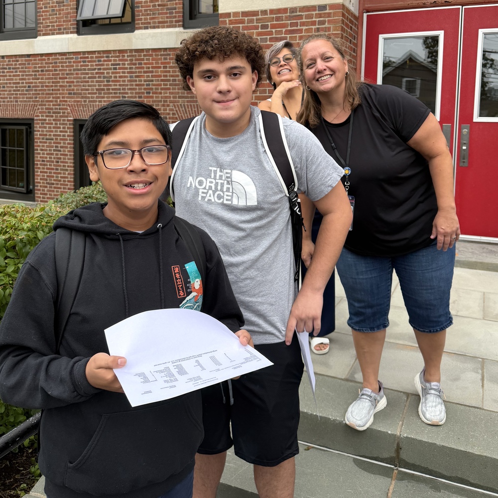 students and educators smile outside on the first day of school