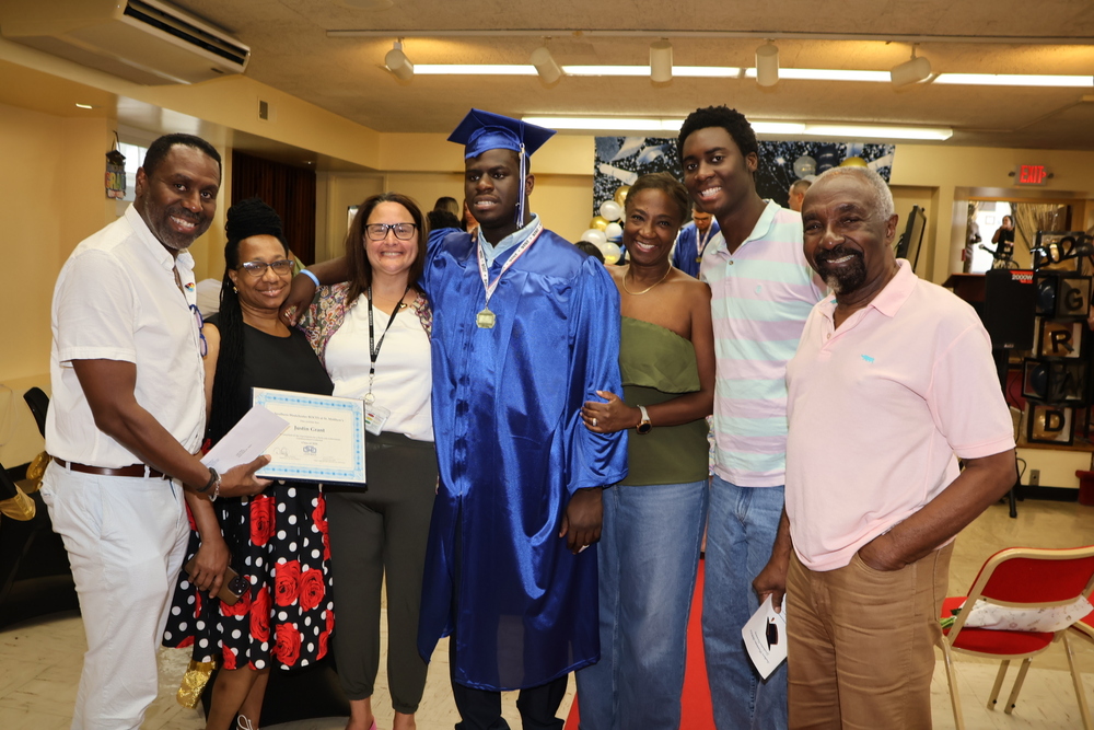 family and teacher surround proud graduate