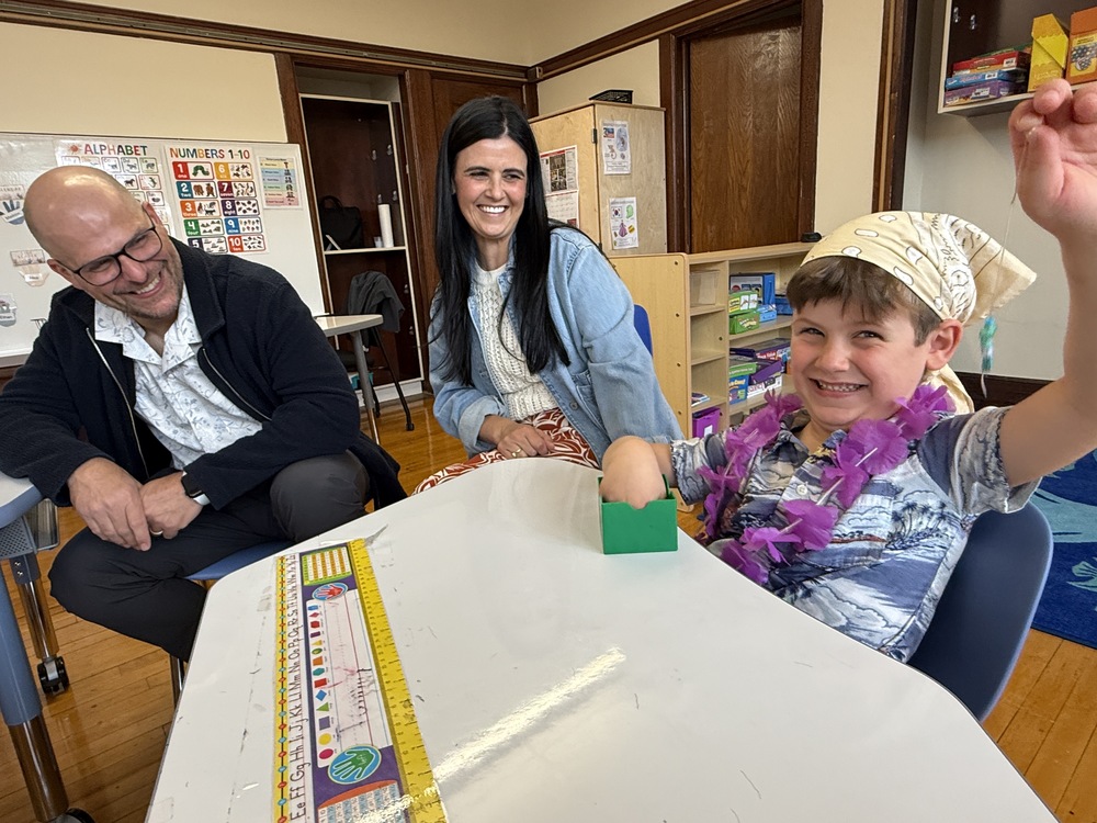 parents smile as student shows off his craft