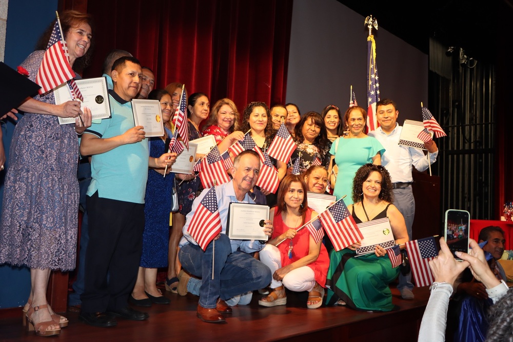 Photo from 2025-26 graduation with new citizen on stage holding mini American flags
