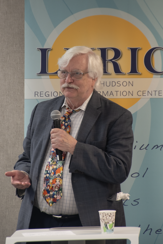 Dr. Chris Dede standing in front of a LHRIC banner