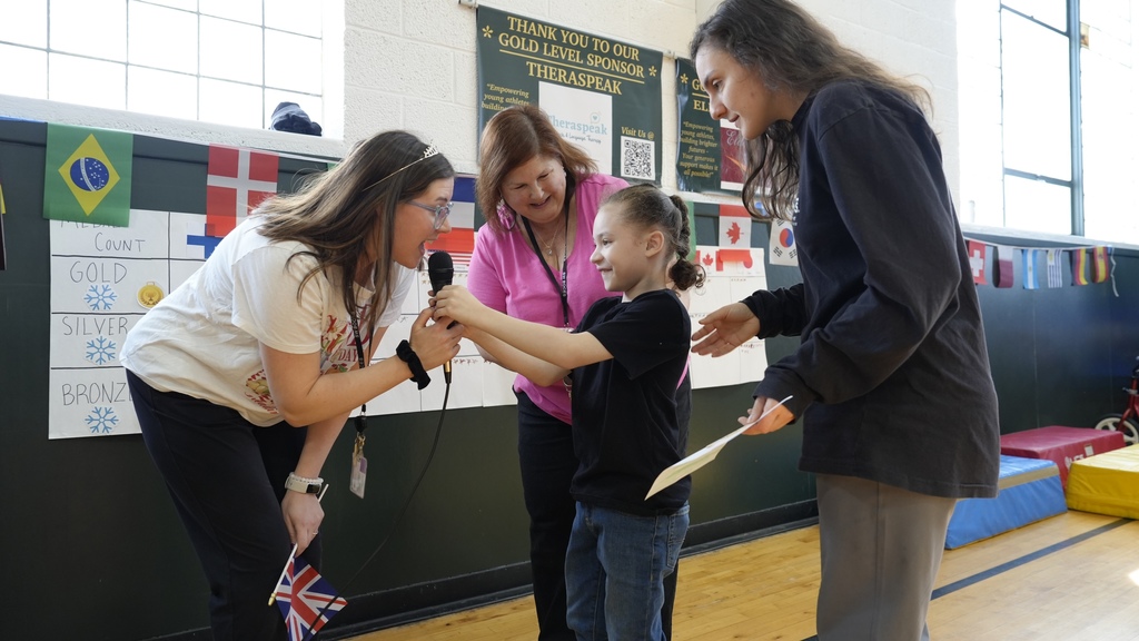 educators present smiling student with medal