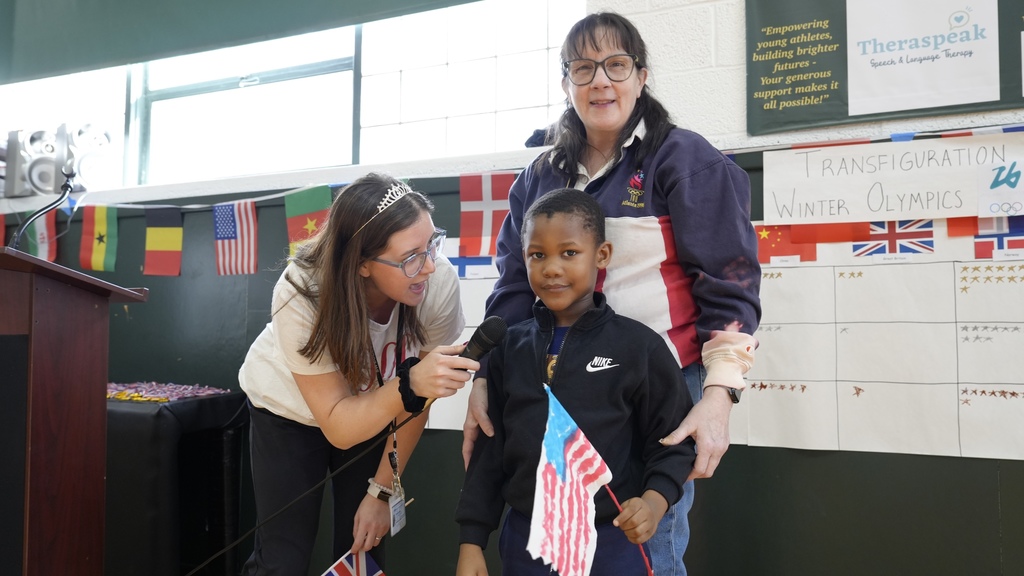 teachers show off student's medal as he holds flag