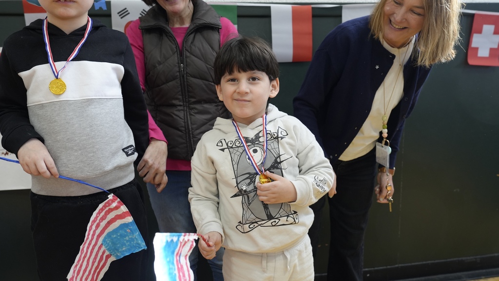 boy holds flag and wears medal among teachers