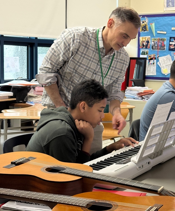 teacher helps student at keyboard