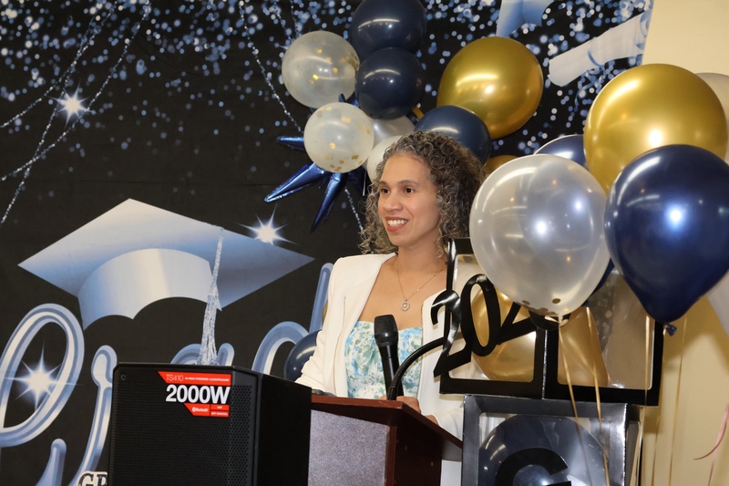 principal smiles amid graduation decor at podium