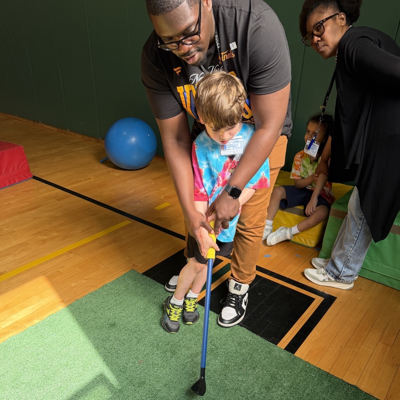 student helped by teacher with golf shot
