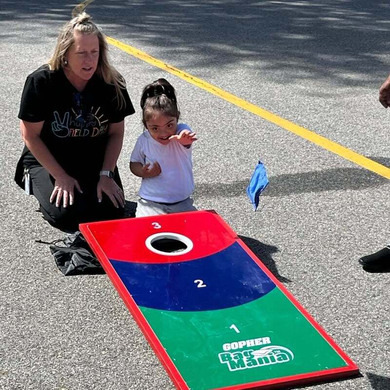 student and teacher play corn hole