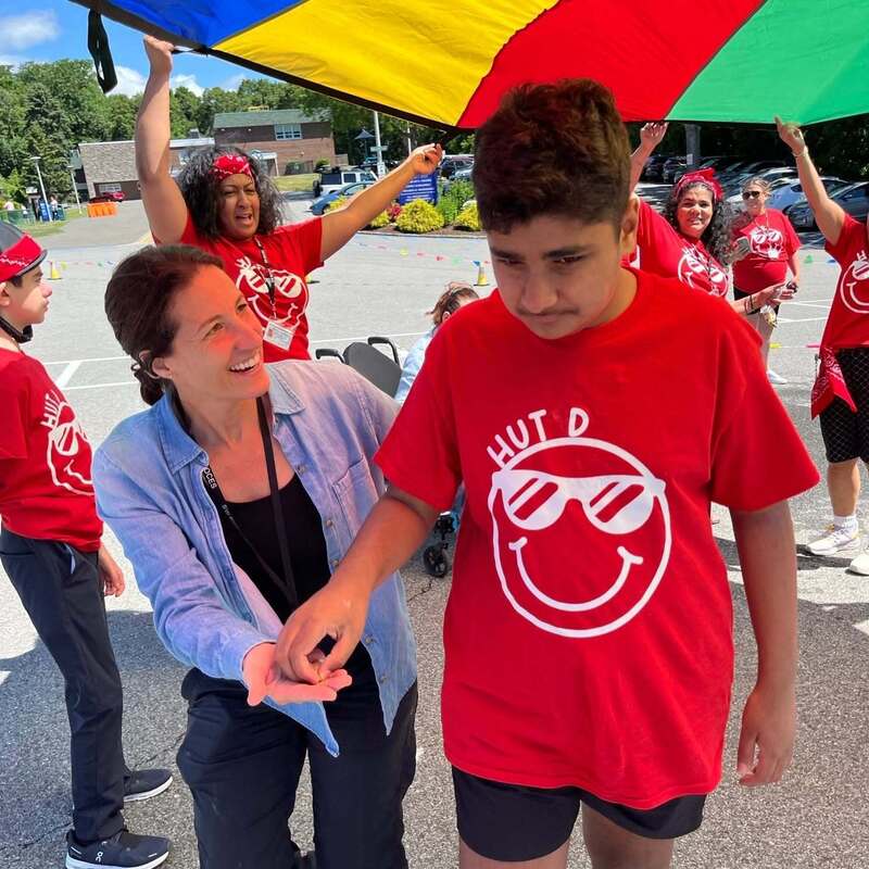 student assisted by teacher beneath parachute game