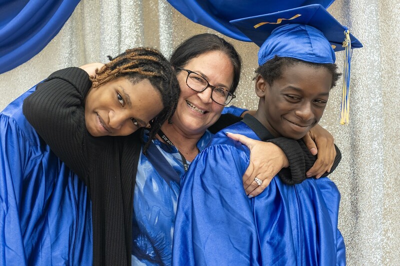 teacher embraces two graduates