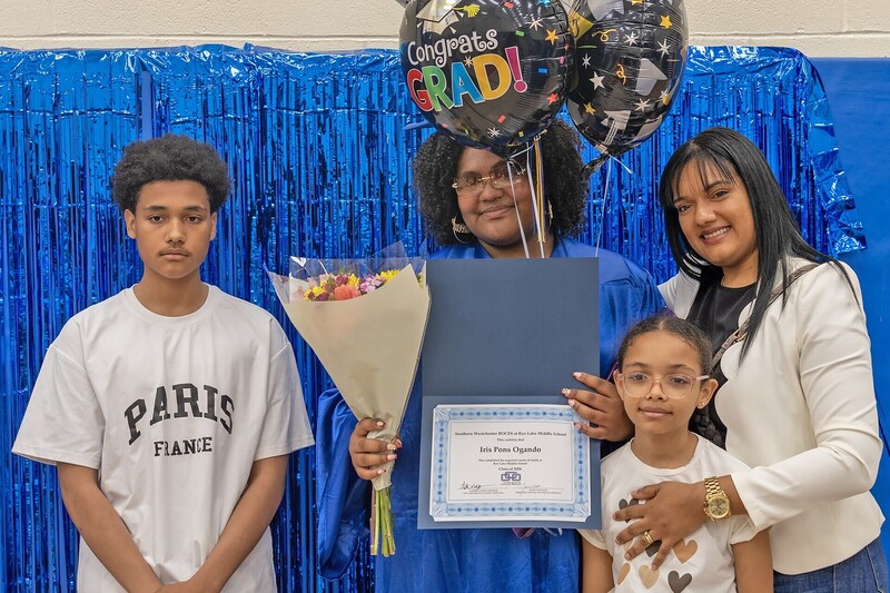 graduate holds big balloon with family around
