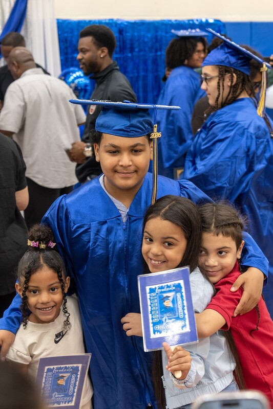 graduate surrounded by young children