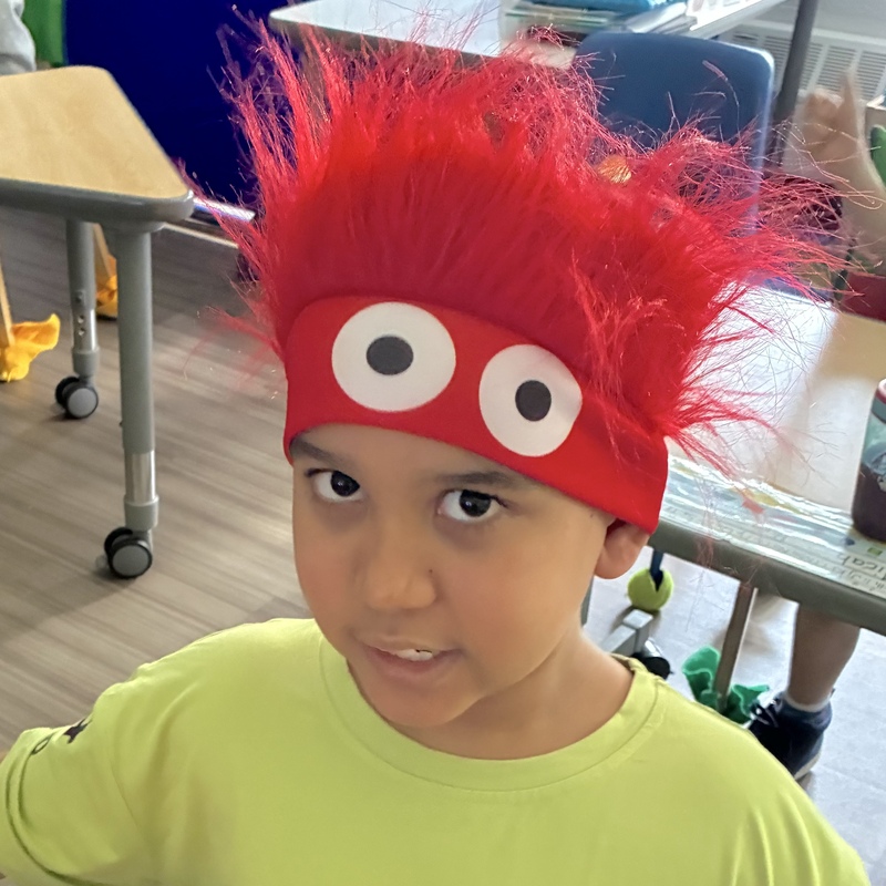 Boy in a hat with googly eyes and red troll hair