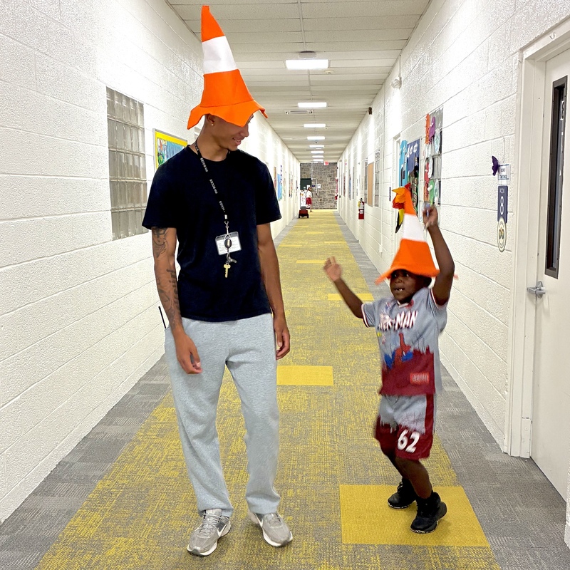teacher and student in hallway wearing traffic cone hats