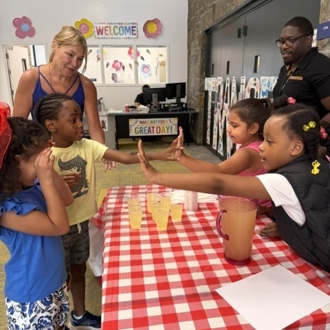 students high five one another at lemonade stand